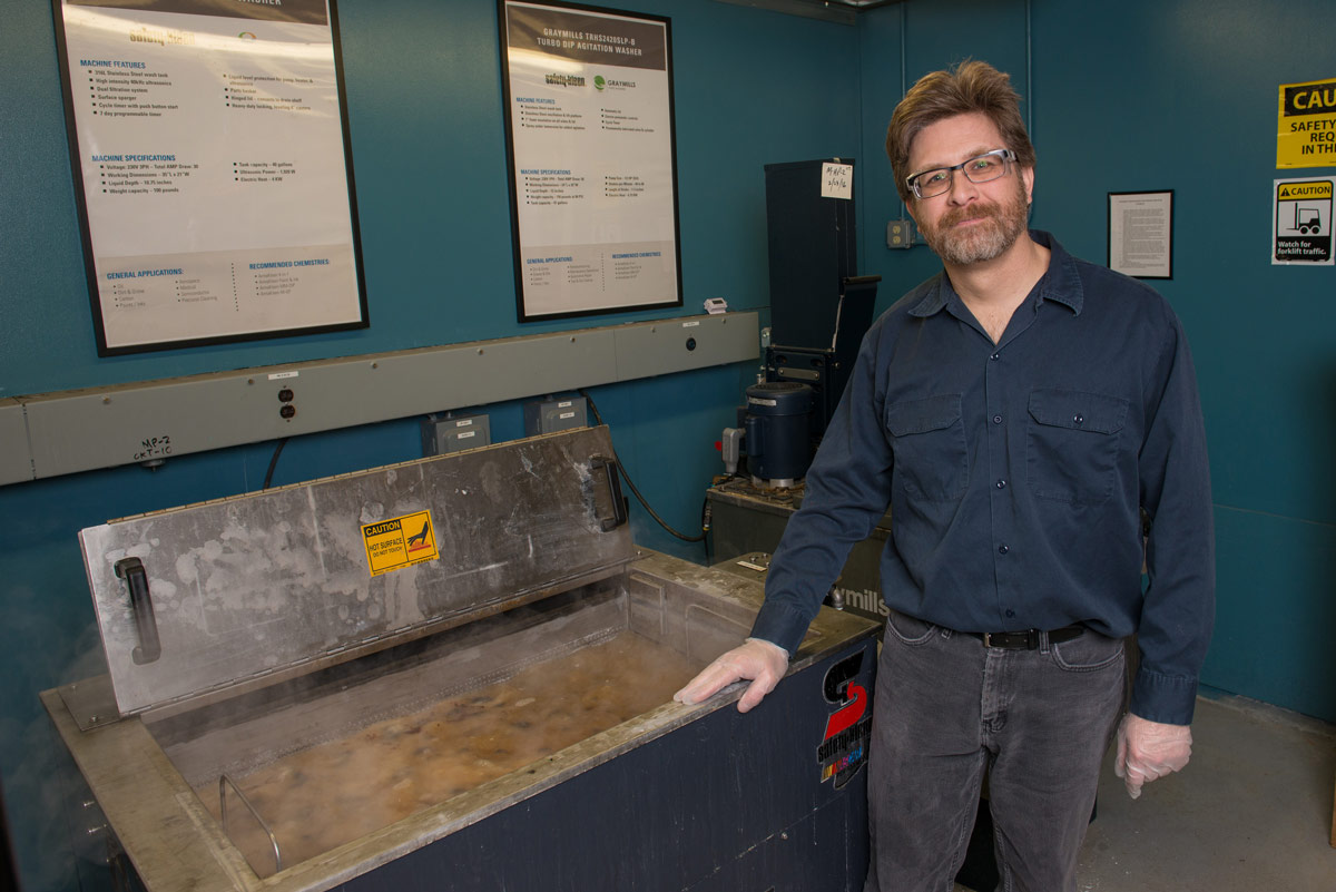 Andy Logan inspects the cleaning solution in an aqueous cleaner.